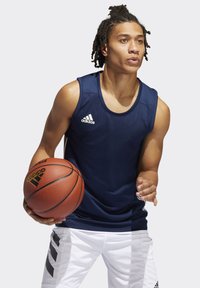 Marineblå ærmeløs basketballtrøje med subtil struktur og Adidas-logo; hvide shorts med sorte sideløse striber. Spilleren holder en basketball.