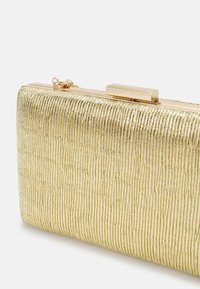 Złoty metaliczny kopertówka z teksturowaną, żeberkową powierzchnią i prostokątnym kształtem. Posiada zapięcie na klamrę oraz gładkie, eleganckie wykończenie.