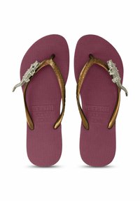 Paarse teenslippers met een textuur op de zolen, voorzien van bronzen banden versierd met een decoratieve zilveren krokodilaccent.