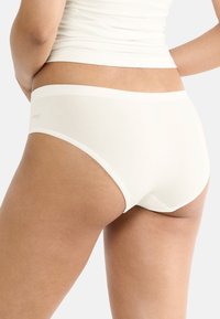 Witte katoenen hipsteronderbroek met een gladde textuur, een brede tailleband en minimale branding aan de zijkant. Gericht op comfort en pasvorm.