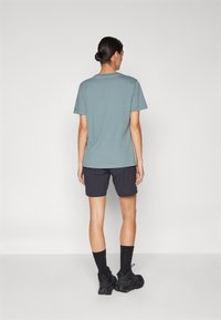 Light blue cotton t-shirt, short sleeves, paired with black shorts. Styled with black socks and chunky sneakers. Simple, casual design.