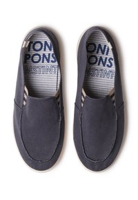 Tumehallid libisevad vabaaja kingad valgete tallade ja triibuliste sisetalladega, millel on sinine tekst, vaadatuna ülevalt valgel taustal.