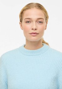 Hele sinine kootud kampsun ümara kaelusega, tekstuurse soonikmustriga ja pikkade varrukatega. Pehme kangaga välimus.