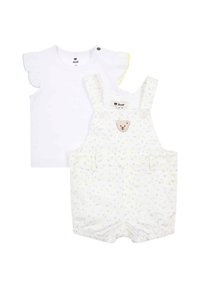 Camicia bianca a maniche corte con maniche arricciate. Salopette a fantasia floreale blu e gialla con applicazione di orsetto sul davanti e chiusure a scatto.