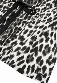 Svart-hvitt leopardmønstret bluse med knytedetalj og innsvingt midje. Laget av lett stoff med glatt tekstur.