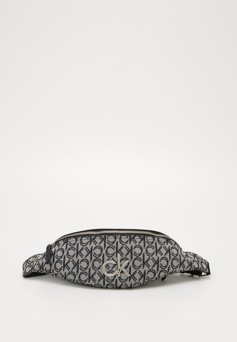 Marsupio a righe in bianco e nero con stampa ripetuta del logo "ck" e emblematico "ck" in metallo sul davanti, dotato di una cerniera superiore e una tracolla regolabile.