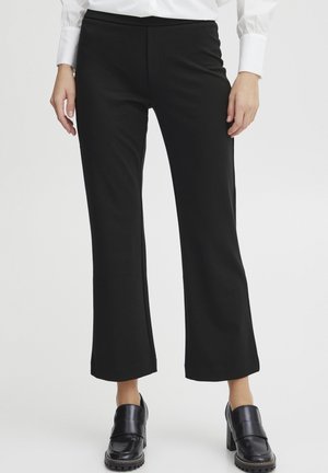 Black flared trousers with a stretchy waistband, made from smooth fabric. Features a slim fit through the hips and a loose fit at the legs.