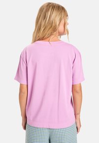 Roze T-shirt met korte mouwen in een ruime pasvorm, met een eenvoudige ontwerp en een ronde halslijn, gecombineerd met licht geruite broek.