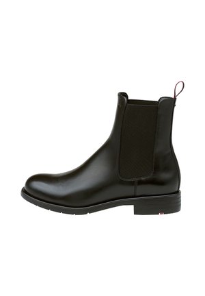 Botín Chelsea de cuero negro con paneles elásticos en los laterales, puntera redonda y tirador. Textura suave, tacón bajo y detalle de marca sutil en el costado.