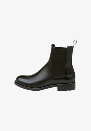 Schwarze Leder-Chelsea-Stiefel mit elastischen Seitenpaneelen, abgerundeter Zehenpartie und Schlaufe. Glatte Textur, niedriger Absatz und dezente Markenkennzeichnung an der Seite.