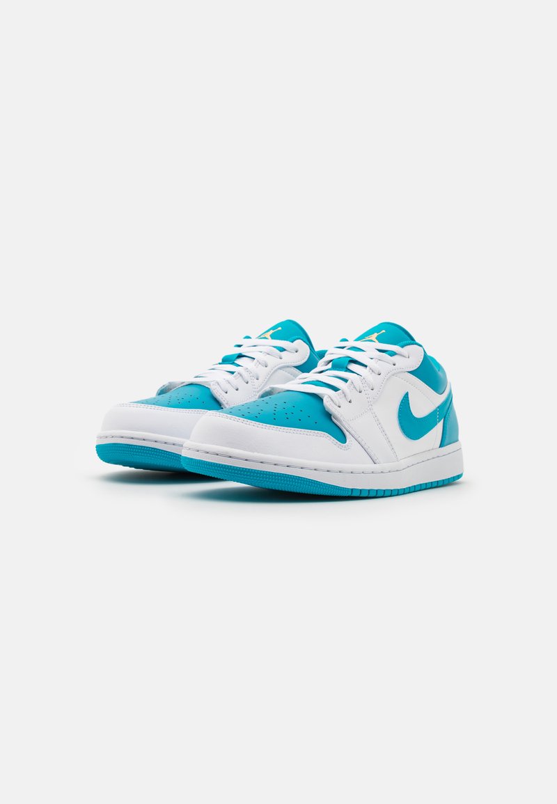 Ein Paar niedrige Nike Sneakers in Weiß und Türkis, mit dem Nike Swoosh und Schnürsenkeln, leicht nach rechts geneigt vor einem weißen Hintergrund.