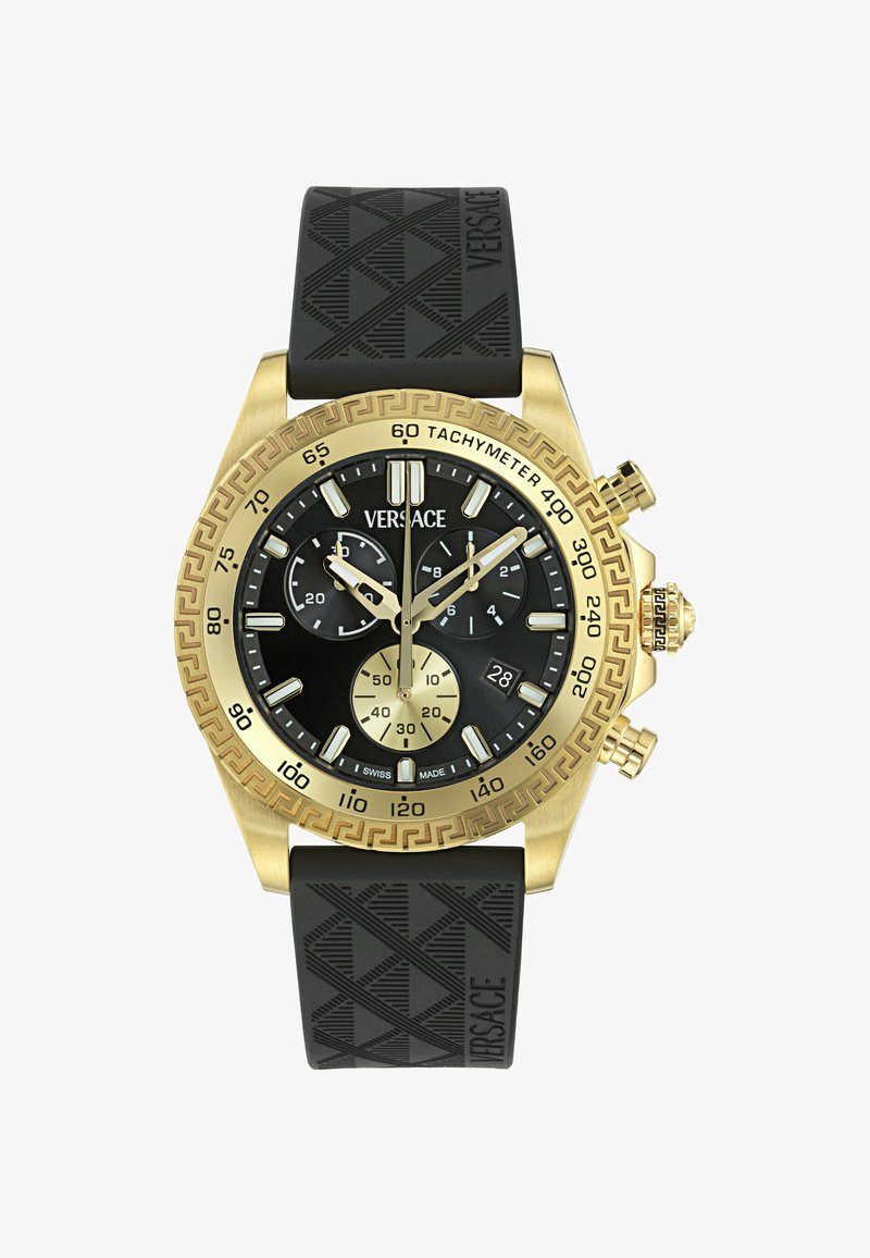 Reloj cronógrafo en tono dorado que presenta una esfera negra con acentos plateados, correa de goma negra, escala taquimétrica y patrón geométrico en la correa.