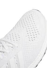 White athletic shoe with a textured mesh upper and white laces. Features a white synthetic overlay and a black rubber sole.