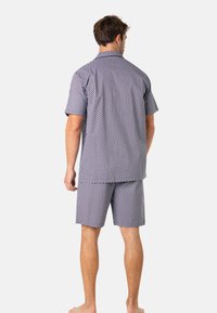 Ensemble de pyjama à manches courtes en bleu marine avec de petits pois blancs, fabriqué en tissu léger, avec une coupe décontractée et un short assorti.