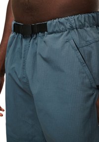 Lichtblauwe shorts van textuurstof, met een elastische tailleband, een zwarte verstelbare riem en zijzakken.