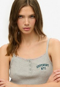 Grijze geribbelde tanktop met kantafwerking, voorzien van twee knopen en "SUPERDRY NYC" in donkergroen geborduurd op de voorkant.