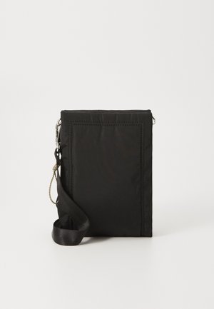 Musta suorakulmainen olkalaukku, jossa on säädettävä hihna ja vetoketjukiinnitys, pystyssä valkoisella tasaisella pinnalla.