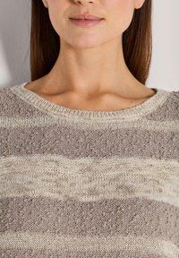 Gebreide pullover in lichtbeige en taupe strepen, met een ronde hals en textuurafwerking, gemaakt van zacht materiaal en met verschillende breipatronen.