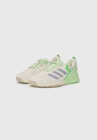 Lightweight athletic shoes in beige mesh with mint green accents, featuring three grey stripes, textured sole, and a unique geometric heel design.