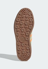Suola di scarpa in gomma marrone con motivi di battistrada circolari e triangolari. Presenta un logo Adidas in rilievo al centro e bordi texturizzati.
