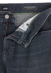 Ciemnoniebieskie dżinsy o ultra slim fit. Posiadają zamek błyskawiczny, metalowy guzik, białą podszewkę i zielone akcenty w szwie.