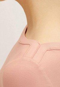 Světlé růžové tričko s měkkou texturou, kulatým výstřihem a jedinečným akcentovým prošíváním poblíž ramen.