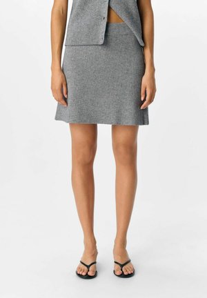 Minifalda de punto acanalado gris con un dobladillo acampanado, textura suave y cintura entallada, combinada con chanclas negras.