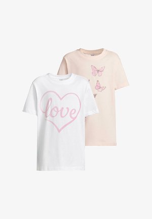 Jasnoróżowa koszulka z grafiką motyla, w połączeniu z czarnymi legginsami i różowymi sneakersami. Krótkie rękawy, luźny krój, gładka tekstura materiału.