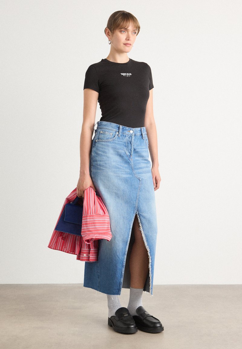 Denim maxi sukně s předním rozparkem, světle modrý omak, roztrhaný lem. Černé přiléhavé tričko, šedé ponožky, masivní černé mokasíny a pruhovaná bunda.