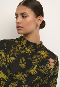 Blusa nera con motivo floreale giallo, con colletto alto, maniche lunghe e dettaglio con bottone sui polsini, realizzata in tessuto leggero.