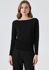 Maglione nero a maglia con collo a barca ampio e maniche lunghe, con dettagli di bottoni ai polsini e una vita aderente.