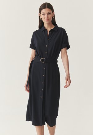 Dunkelblaues Knopfhemdkleid mit kurzen Ärmeln, einem taillierten Gürtel mit runder Schnalle und einem entspannten Schnitt, der bis zur Mitte der Wade reicht.