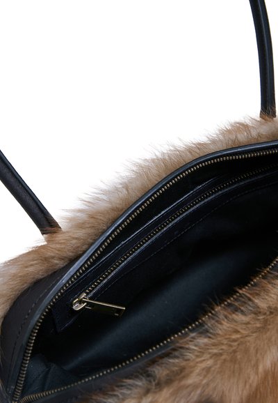 Sac à main noir ouvert avec garniture en fourrure marron, montrant la doublure intérieure noire et une poche zippée avec tirette dorée.