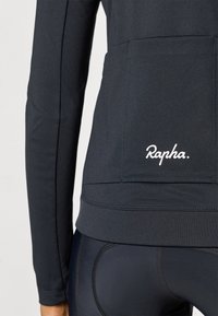 Černá technická bunda s dlouhými rukávy, na spodním okraji s bílým logem "Rapha". Hladká textura a přiléhavý střih.