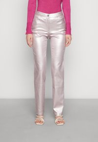 Metalliska rosa raka byxor med en slät textur, med knappknäppning fram och sidofickor. Bärs med krämfärgade sandaler med remmar.