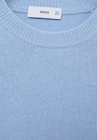 Pulover tricotat de culoare albastră deschisă, cu un guler cu fâșii. Textura este moale și texturată, având un etichetă care indică mărimea și marca.