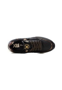Zapatilla deportiva negra con acentos dorados, tejido texturizado y diseño de cordones. Cuenta con un lado con cremallera y un cuello acolchado para mayor comodidad.