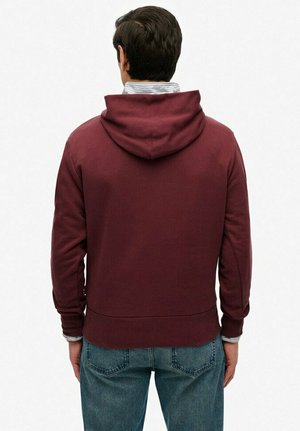 Bordeaux hoodie met een zachte textuur, geribde manchetten en tailleband. De achterkant heeft een gebogen zoomontwerp en een losse pasvorm.