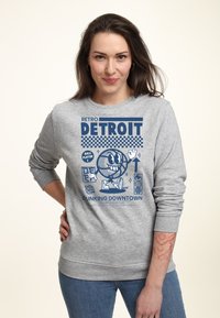 Felpa in cotone grigia con un design grafico retro blu che presenta la scritta "RETRO DETROIT" e immagini di un pallone da basket e di un giocatore, maniche lunghe.