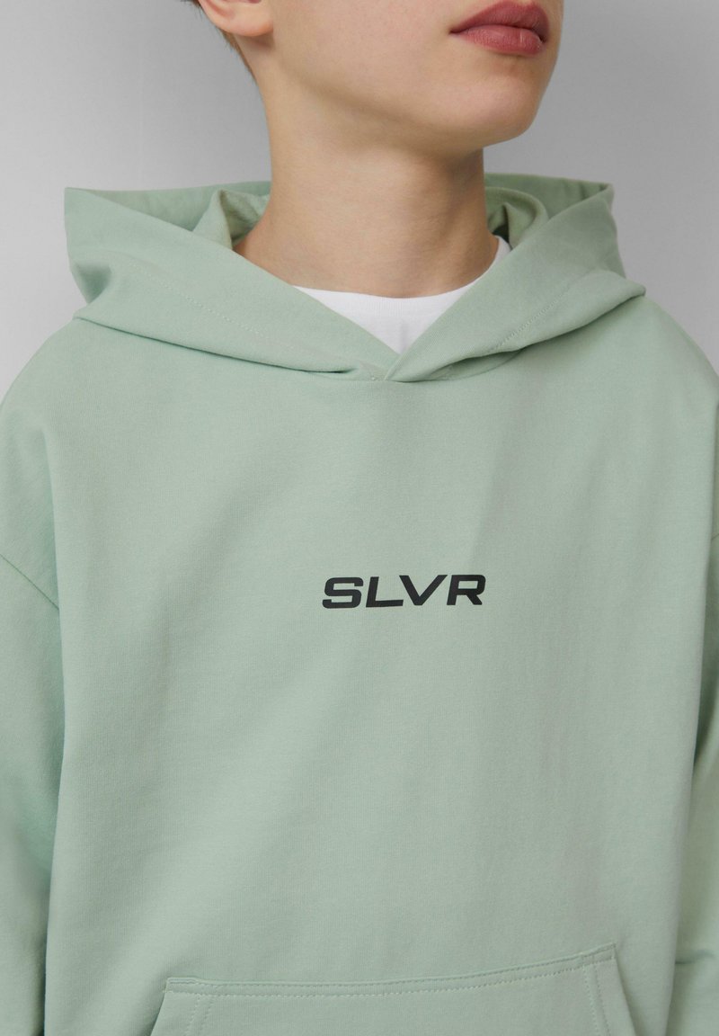 Mintgroene hoodie met een centraal zwart "SLVR" logo, gemaakt van zachte stof met een kangoeroezak en een capuchon met trekkoord.
