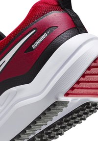 Baskets de course rouge et noire avec un dessus en mailles texturées, semelle en caoutchouc avec des stries pour une meilleure adhérence, et un intermédiaire en mousse blanche.
