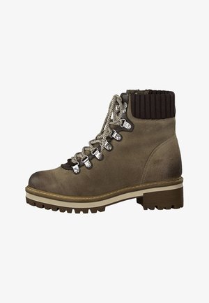 Brązowy zamszowy but trekkingowy z prążkowanym, dzianinowym kołnierzem, srebrnymi detalami i kontrastującą beżową podeszwą; posiada sznurowane zapięcie z przodu i grubą podeszwę z bieżnikiem.