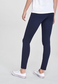 Mariniere leggings van een gladde, rekbare stof, met een aansluitend ontwerp en subtiele zijnaden, gecombineerd met witte low-top sneakers.
