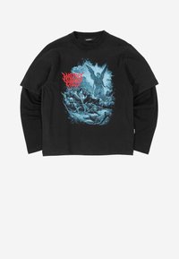 Melna garenmēte t-kreklā ar zilu grafiku, kur attēlots eņģelis starp figūrām, ar sarkanu tekstu virs mākslas darba. Izgatavots no kokvilnas, brīvā piegriezumā.