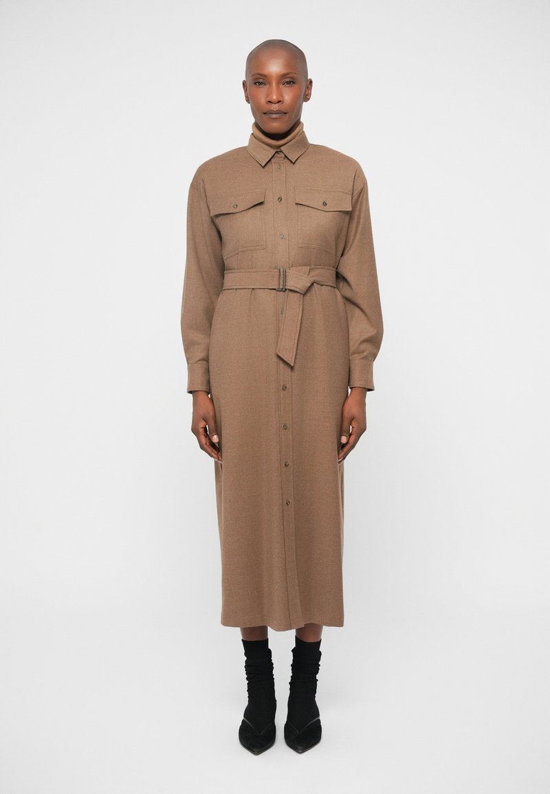 Vestido castanho de manga longa em tecido texturizado, com uma frente com botões, dois bolsos no peito e uma cintura cingida com um cinto a condizer.