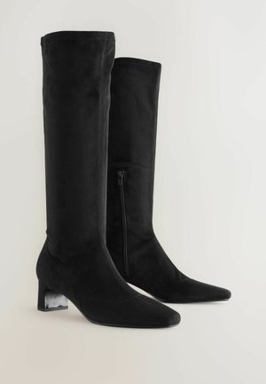 Bottes en daim noires montantes avec des bouts pointus, finition texturée et un talon en bloc. Fermeture éclair sur le côté pour un enfilage facile.