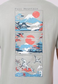 Série de trois panneaux de style japonais montrant le mont Fuji, des temples, un soleil rouge, des grues, des vagues et des fleurs de cerisier sur un fond gris clair.