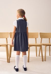 Grå denimkjole med plisseret nederdel, hvid kortærmet bluse, hvide knæstrømper med blonde mønster og sorte sko.