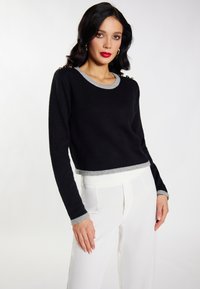 Pulover scurt negru cu guler și tiv gri ribat. Mâneci lungi cu mansete gri și accesorii decorative la umăr.