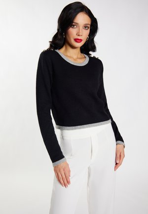 Schwarzer, verkürzter Pullover mit einem grauen, gerippten Halskragen und Saum. Lange Ärmel mit grauen Bündchen und dekorativem Beschlag an der Schulter.